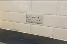 Image of a double electrical socket set in a white tiled wall